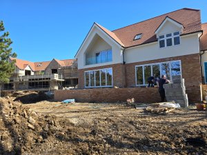 Construction site with scaffolding and visible progress on both the retrofit and new build homes.