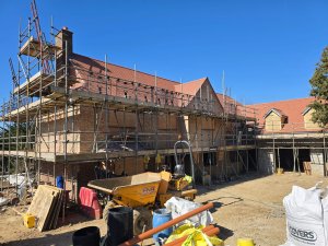 Construction site with scaffolding and visible progress on both the retrofit and new build homes.